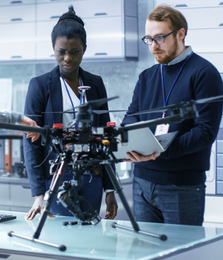 Two scholars working on a robotics project with a laptop in-hand.